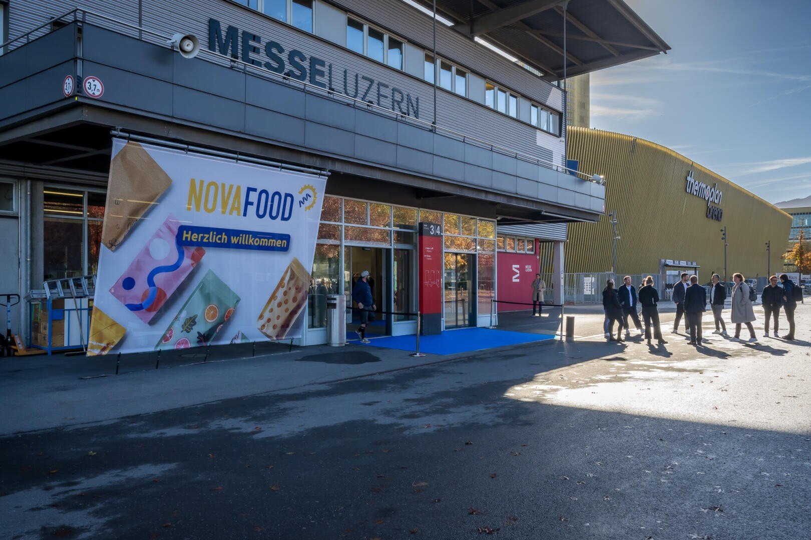 Außenansicht des Messe Luzern-Kongresszentrums mit einem großen NovaFood-Banner, das am Eingang hängt.
