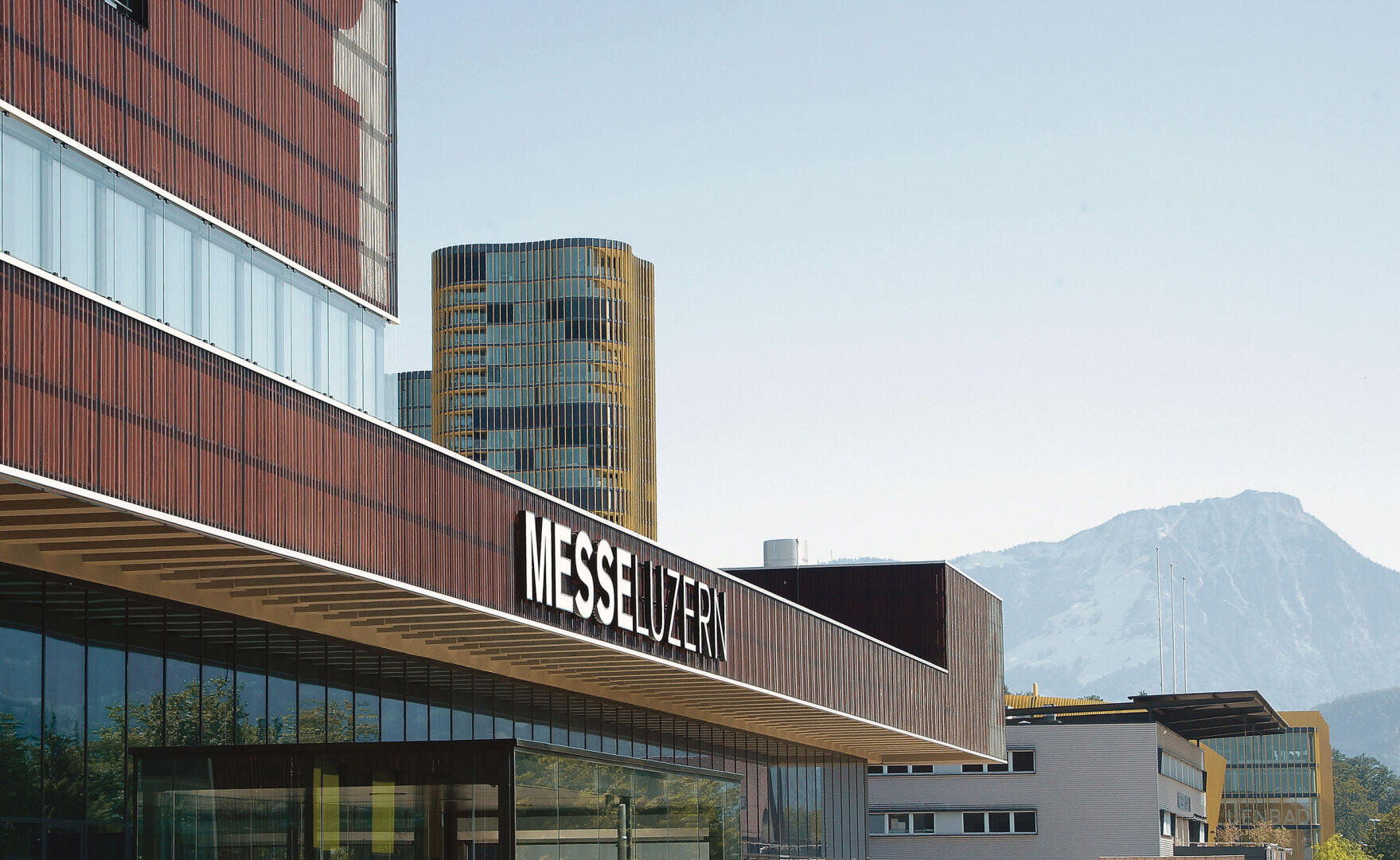 Moderner Gebäudekomplex mit dem Schriftzug MESSE LUZERN und einem schneebedeckten Berg im Hintergrund.